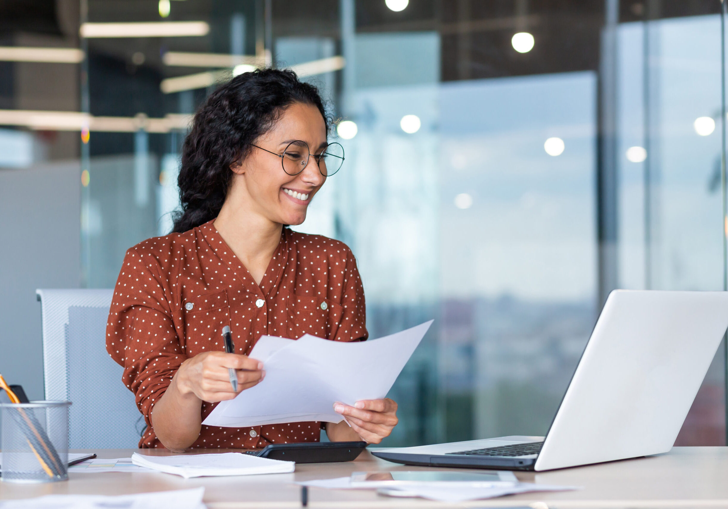 Successful satisfied and happy business woman working inside modern office, hispanic woman in glasses and shirt using laptop at work,